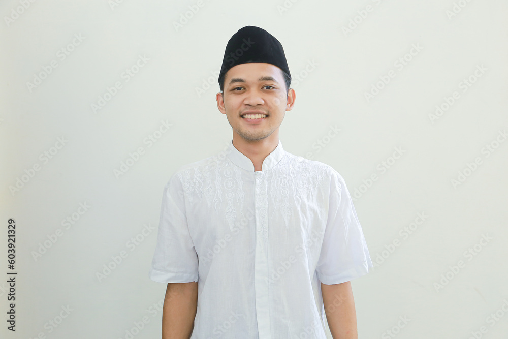Optimistic handsome young Asian Muslim man in Arabic costume standing with crossed arms and looking at camera with toothy smile isolated on white background. People religious Islamic lifestyle concept Optimistic handsome young Asian Muslim man in Arabic costume standing with crossed arms and looking at camera with toothy smile isolated on white background. People religious Islamic lifestyle concept