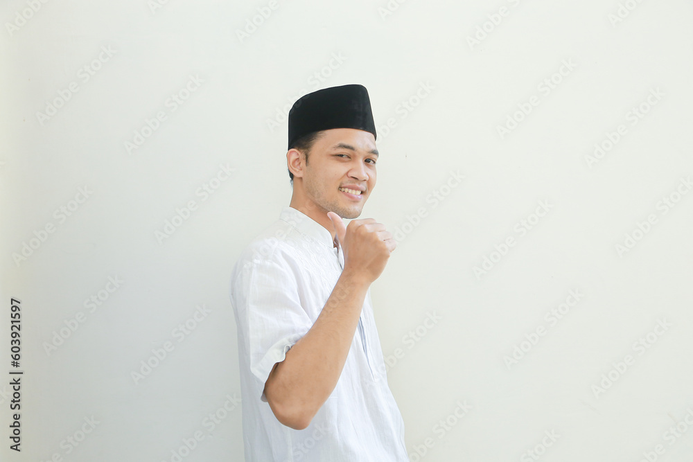 Excited young Asian Muslim man raising fists and celebrating victory on Ramadan isolated over white background. People religious Islam lifestyle concept Excited young Asian Muslim man raising fists and celebrating victory on Ramadan isolated over white background. People religious Islam lifestyle concept