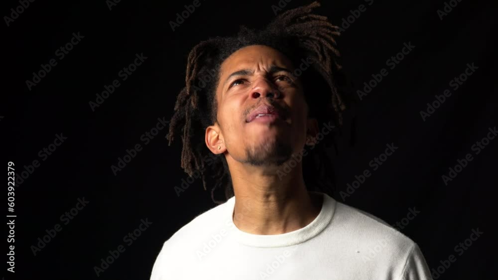 Frustrated young black man screaming at the top of his lungs, black background Frustrated young black man screaming at the top of his lungs, black background