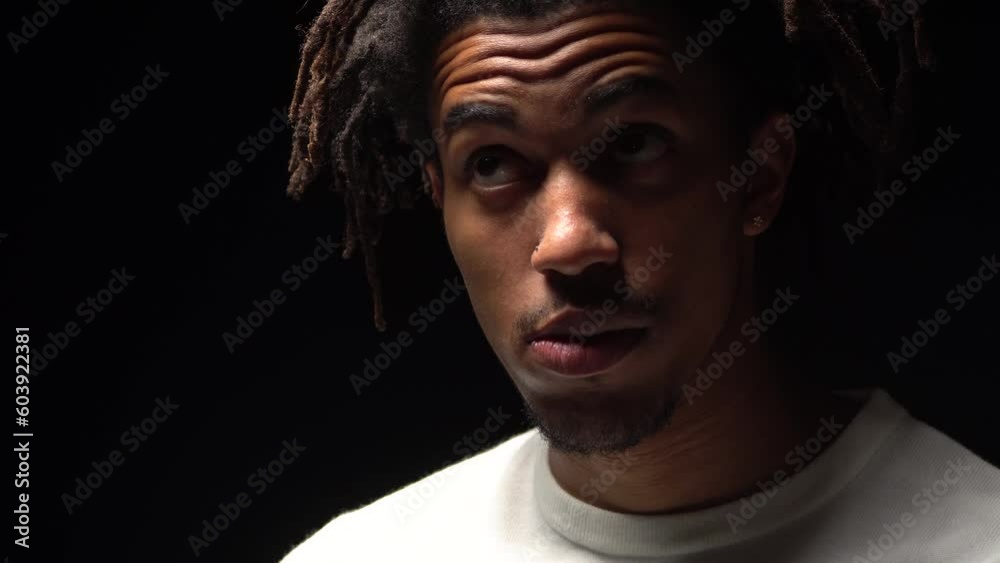 Portrait of a young black man looking at different sides and thinking, black background Portrait of a young black man looking at different sides and thinking, black background