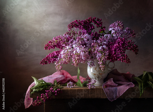 Still life with a bouquet of lilacs on a wooden table against a dark background