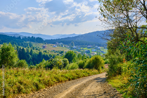 landscape dirt road in the mountains with a turn. Blue mountains background. Sunny weather in the Carpathians