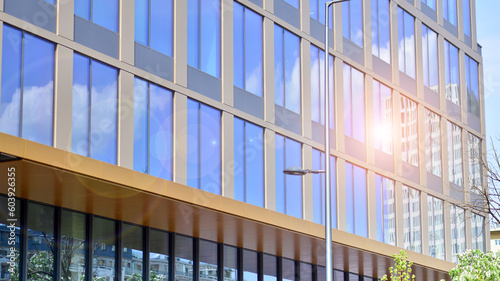  Reflection of modern commercial building on glass with sunlight. Eco architecture. Green tree and glass office building. The harmony of nature and modernity. 