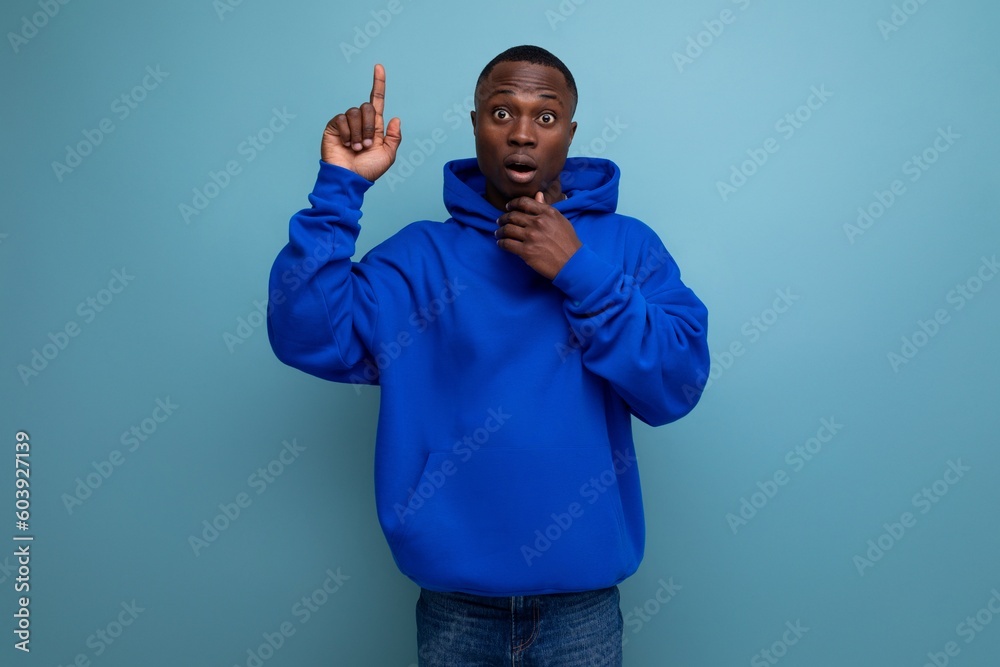 Fototapeta premium close-up of a serious pensive american young guy in a sweatshirt with a hood on a studio background with copy space