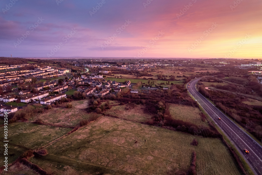 Aerial sunset scene with view on a highway and town residential and commercial area. Galway city, Ireland. Rich saturated warm and cold colors. Dramatic sky.