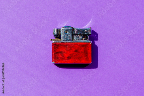 Antique metal red lighter flat lay on purple background.Copy space.