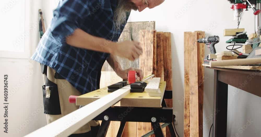 DIY woodworking, man draws cutting marks on wood slat fixed into vise grip using measuring tape and carpenter's pencil, close up, real people DIY woodworking, man draws cutting marks on wood slat fixed into vise grip using measuring tape and carpenter's pencil, close up, real people