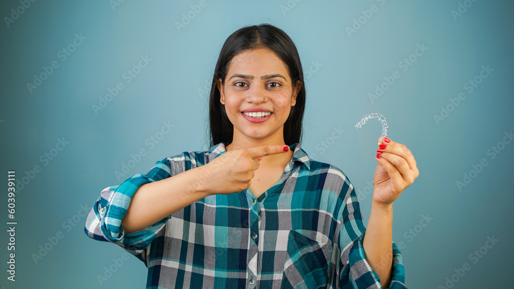 Young Asian Indian woman holding removable invisible aligner, also known as invisalign or clear aligner Young Asian Indian woman holding removable invisible aligner, also known as invisalign or clear aligner