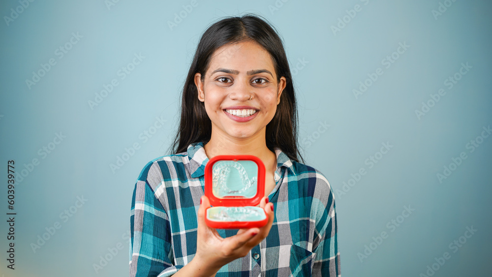 Young Asian Indian woman holding removable invisible aligner, also known as invisalign or clear aligner Young Asian Indian woman holding removable invisible aligner, also known as invisalign or clear aligner