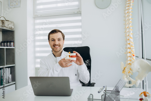 a vertebrologist doctor works on a camera behind a laptop photo