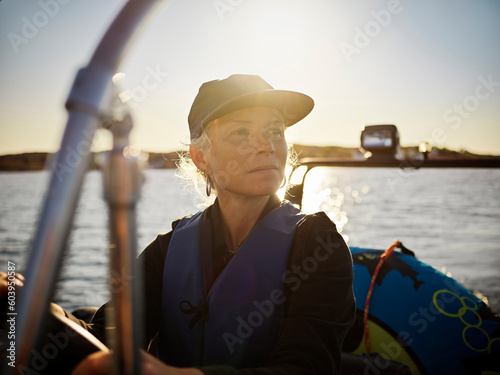 Woman driving boat on sea during sunset