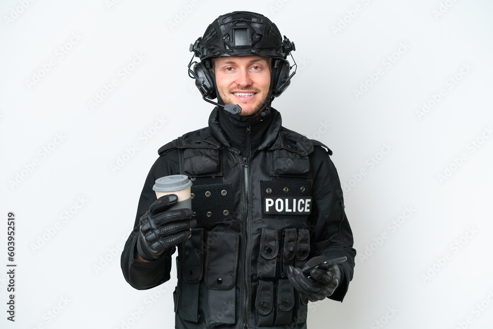 SWAT man over isolated white background holding coffee to take away and a mobile SWAT man over isolated white background holding coffee to take away and a mobile