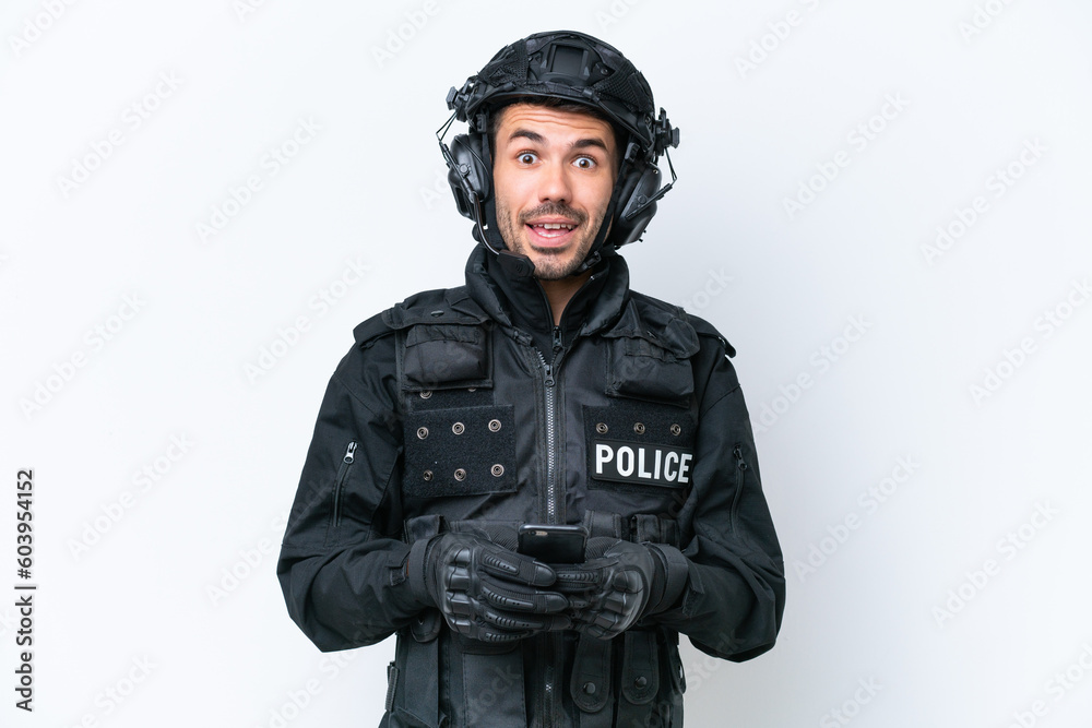 Young caucasian SWAT man isolated on white background surprised and sending a message Young caucasian SWAT man isolated on white background surprised and sending a message