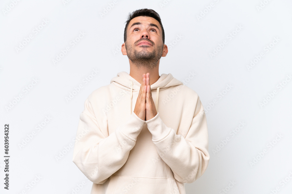Young caucasian man isolated on white background keeps palm together. Person asks for something
