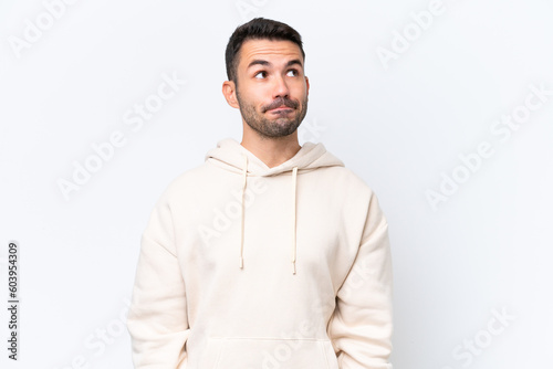 Young caucasian man isolated on white background having doubts while looking up © luismolinero
