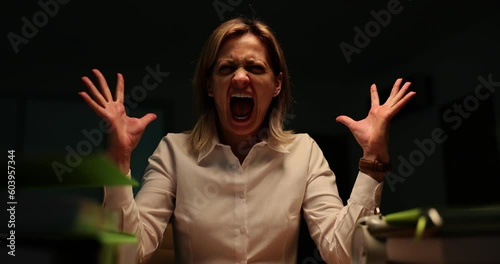 Portrait of a manager woman screaming in the evening in office and going crazy at work. Overtime and burnout at work