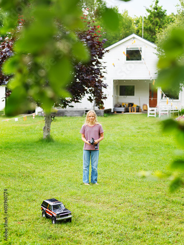 Girl playing with remote control car on lawn photo