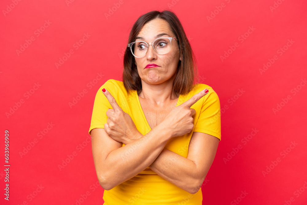 Middle-aged caucasian woman isolated on red background pointing to the laterals having doubts Middle-aged caucasian woman isolated on red background pointing to the laterals having doubts