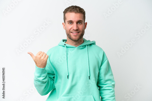 Young handsome caucasian man isolated on white background pointing to the side to present a product © luismolinero