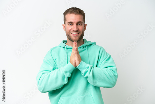 Young handsome caucasian man isolated on white background keeps palm together. Person asks for something © luismolinero