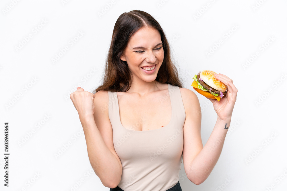 Young caucasian woman holding a burger isolated on white background celebrating a victory Young caucasian woman holding a burger isolated on white background celebrating a victory