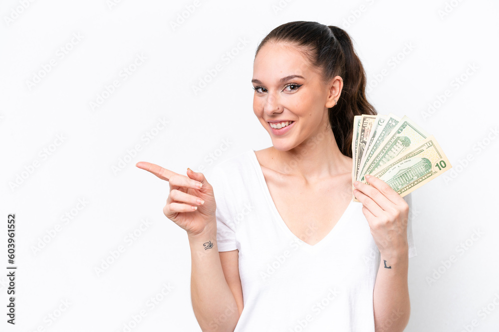 Young caucasian woman taking a lot of money isolated on white background pointing finger to the side Young caucasian woman taking a lot of money isolated on white background pointing finger to the side