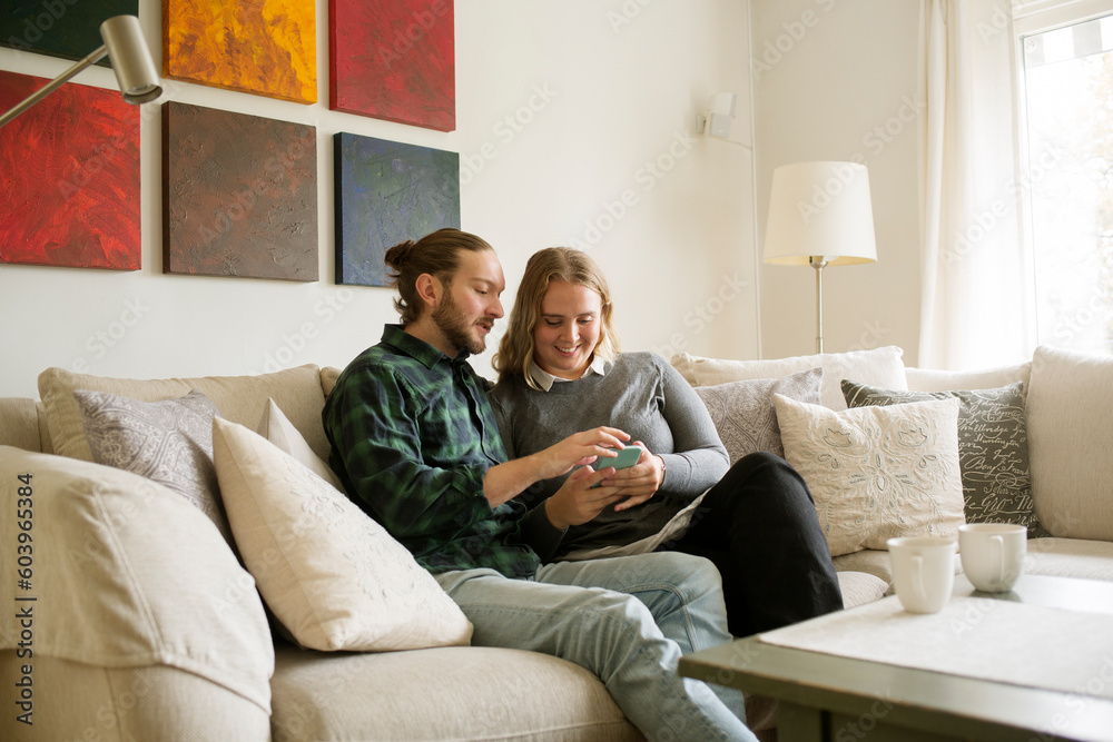 Couple using smart phone on sofa Couple using smart phone on sofa