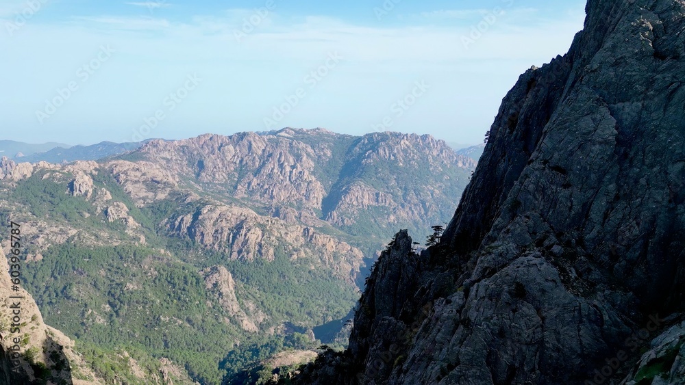 Breathtaking Aerial Vista: A Journey Within the 'Trou de la Bombe', Aiguilles de Bavella, Corsica - Majestic Sunlit Peaks and Rugged Terrains Stretching into Infinity