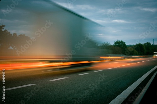 A truck driving on the highway at dusk. Motion blur on the highway. Evening shot of a truck. Concept of international transport and logistics. © romannerud