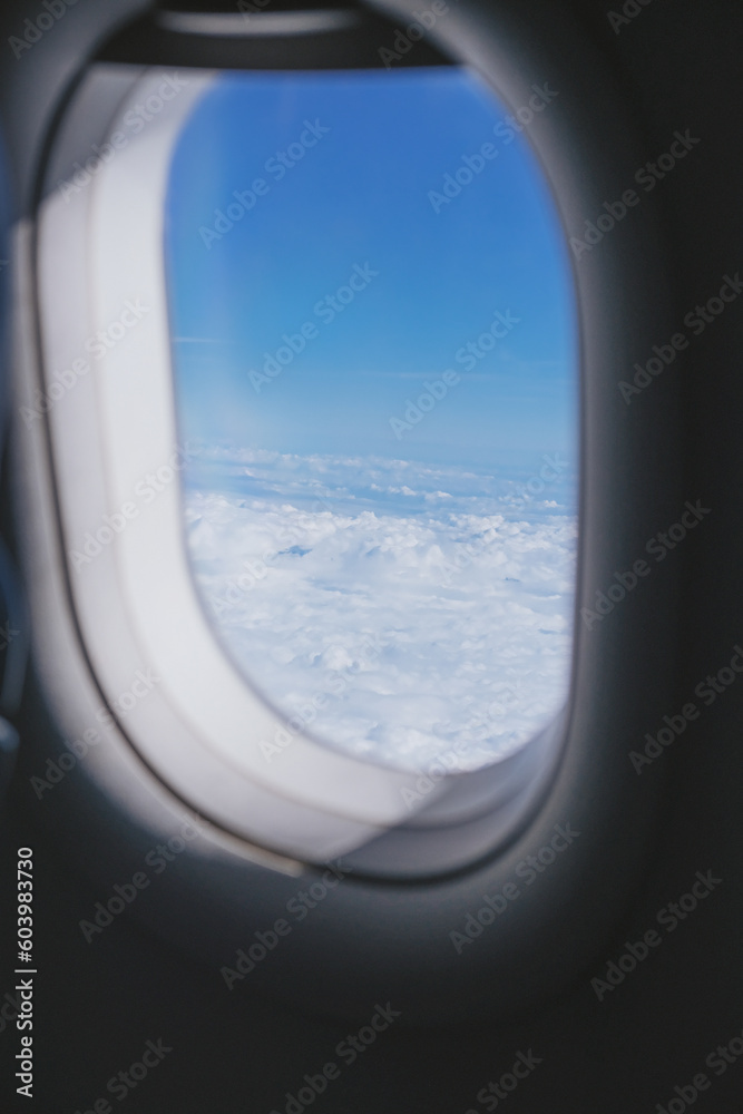 An airplane window with blue sky and cloud outside An airplane window with blue sky and cloud outside