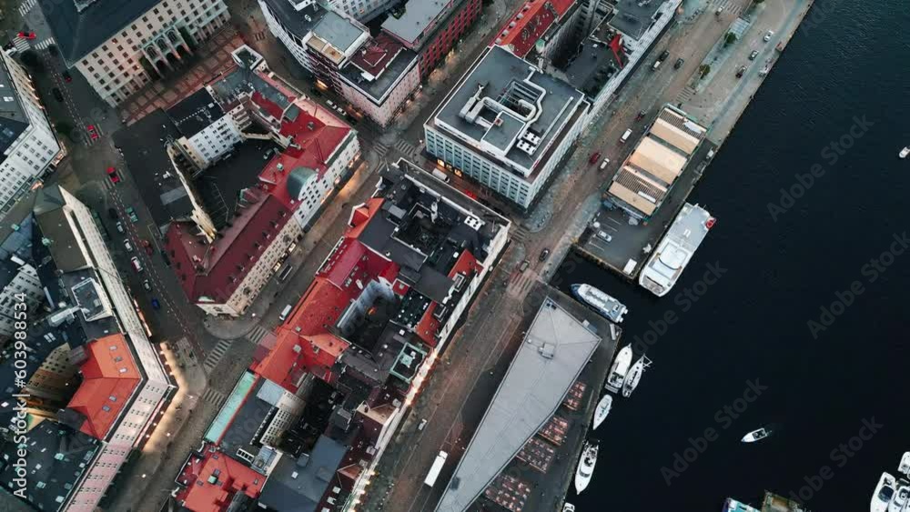 Top down tracking shot of a small port with boats, houses and streets, some cars are seen along a river, daytime, no people, aerial view Top down tracking shot of a small port with boats, houses and streets, some cars are seen along a river, daytime, no people, aerial view