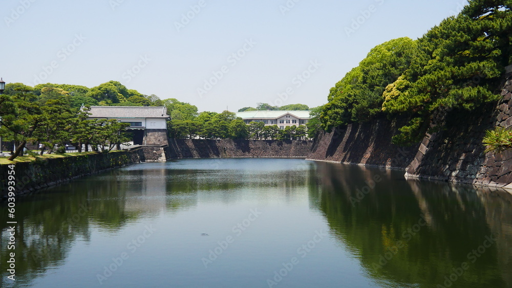 Promenade au bord d'un grand mur ou muraille du jardin impérial de Tokyo, avec un lac transparent et limpide, des arbres au-dessus du mur, cité incourtounable et touristique, en plein centre ville