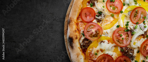 cheesy meaty pizza with tomatoes, onions, and sweet peppers, close-up