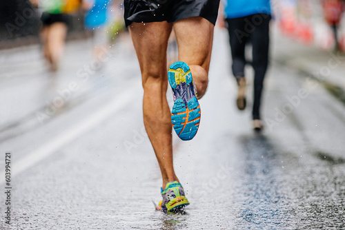 close-up runner athlete run marathon race on wet asphalt, water drops on sole running shoes