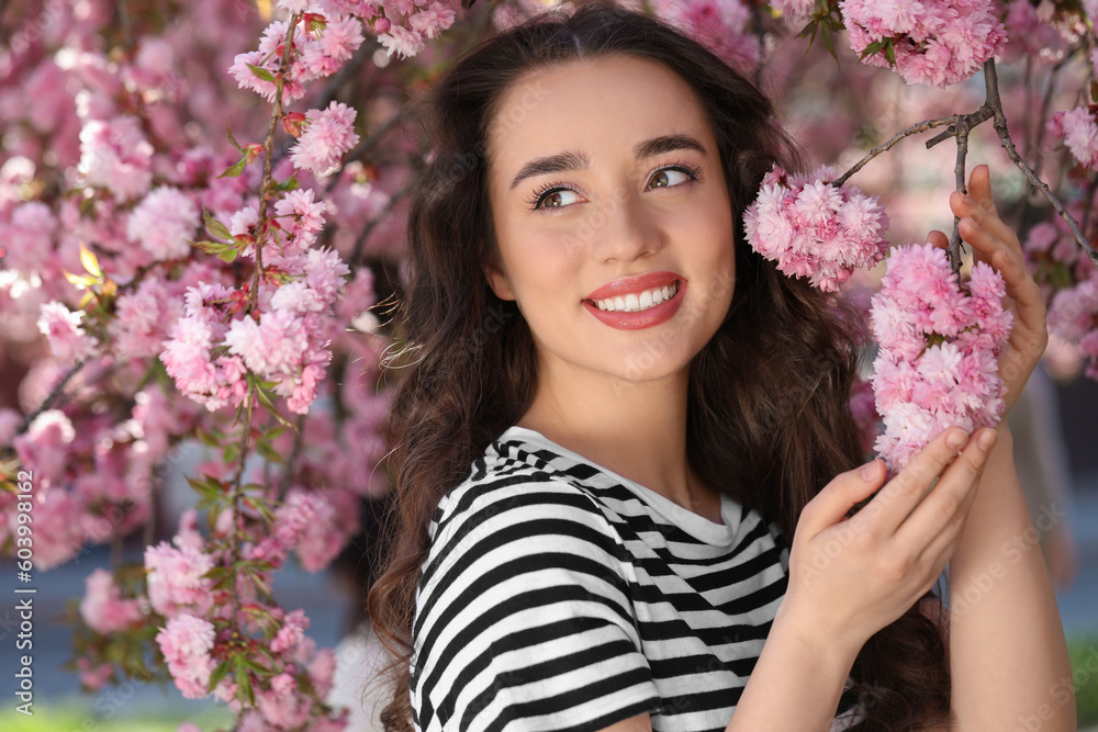 Beautiful woman near blossoming sakura tree on spring day