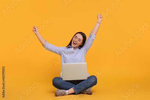 Happy young woman with laptop on yellow background © New Africa