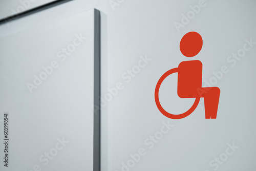 Special needs accessible public toilet sign on white wall, closeup. Wheelchair symbol