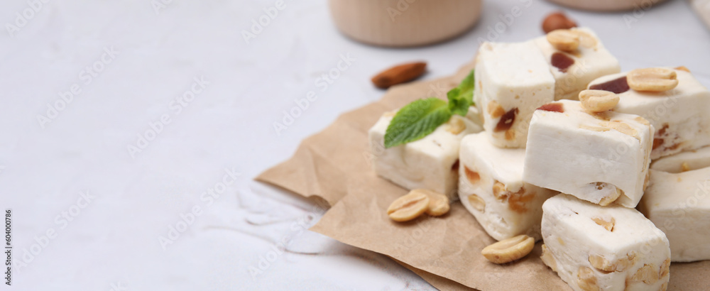 Pieces of delicious nutty nougat on white table, space for text. Banner design