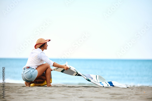 Canvas Print Young woman spreading towel on beach.