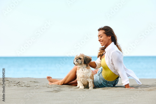 Young happy woman spending summer day on beach with her dog.