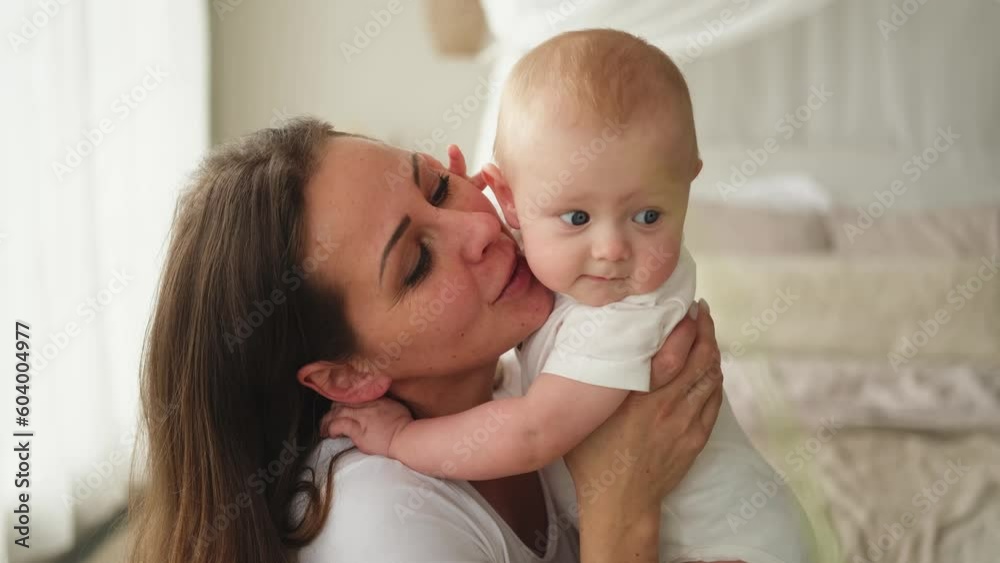 Happy family at home. Mother holding little toddler child daughter. Mom and baby girl relax playing having fun together at home. Mother hugging kissing baby with love care. Mom of breast feeding baby