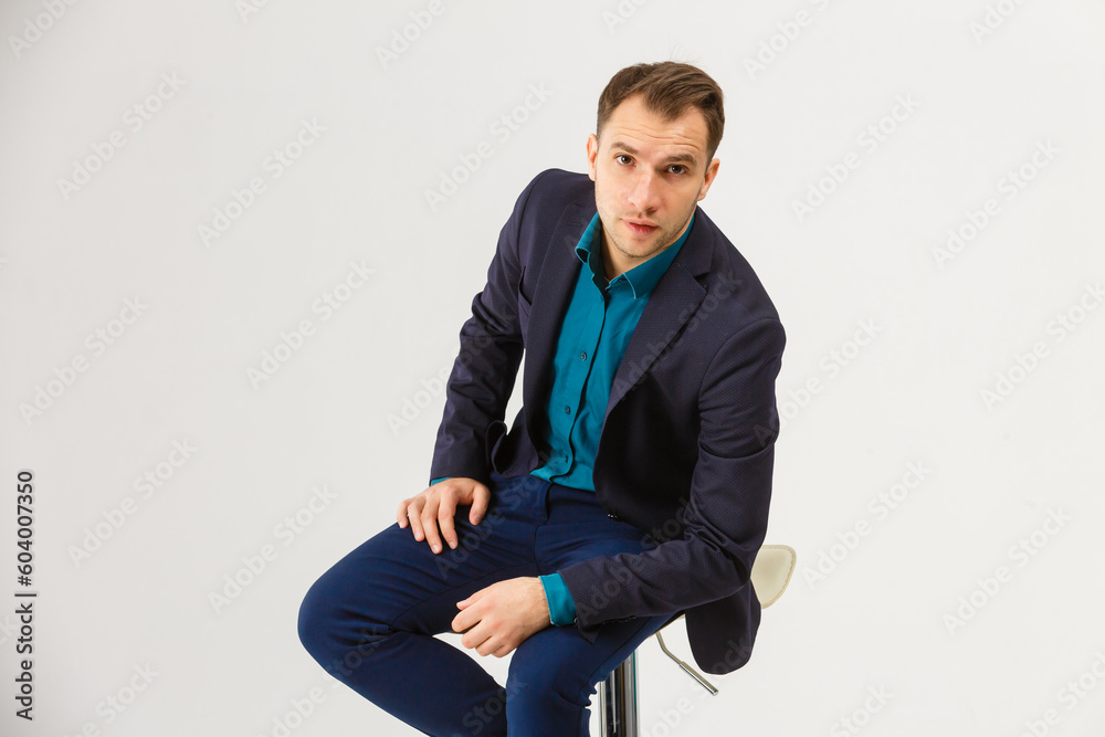 Proud and satisfied young man sitting on chair and looking at camera isolated on white background Proud and satisfied young man sitting on chair and looking at camera isolated on white background