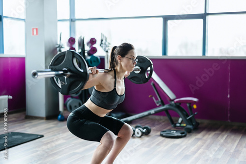 Young woman working out with a barbell at the gym  