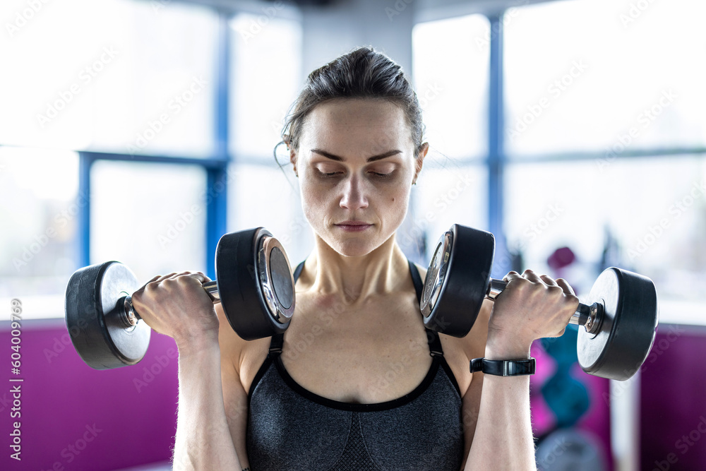 Young woman exercising with dumbbells in a health club
Young woman exercising with dumbbells in a health club
