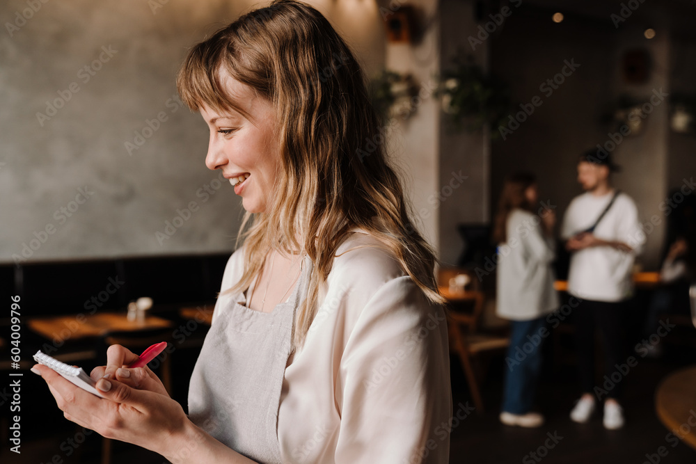 Cute young blonde waitress writes down order in cafe Cute young blonde waitress writes down order in cafe