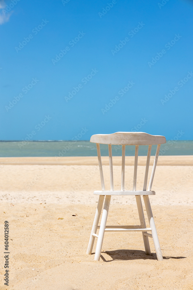 Old white painted wooden chair on a paradisiacal beach