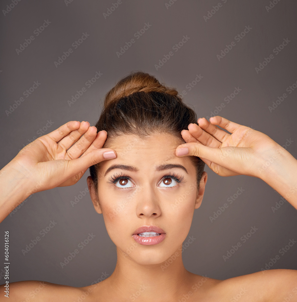 Fototapeta premium Stress, touching and a woman with face wrinkles isolated on a dark background in a studio. Concern, anxiety and a young girl frustrated with skincare, filler and a facial beauty cosmetics mistake