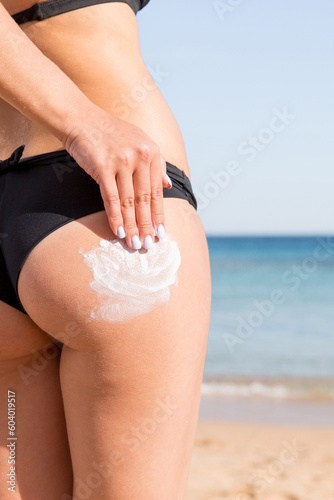 Wallpaper Mural Woman hand is applying suntan cream on her buttocks at the beach at the sea back