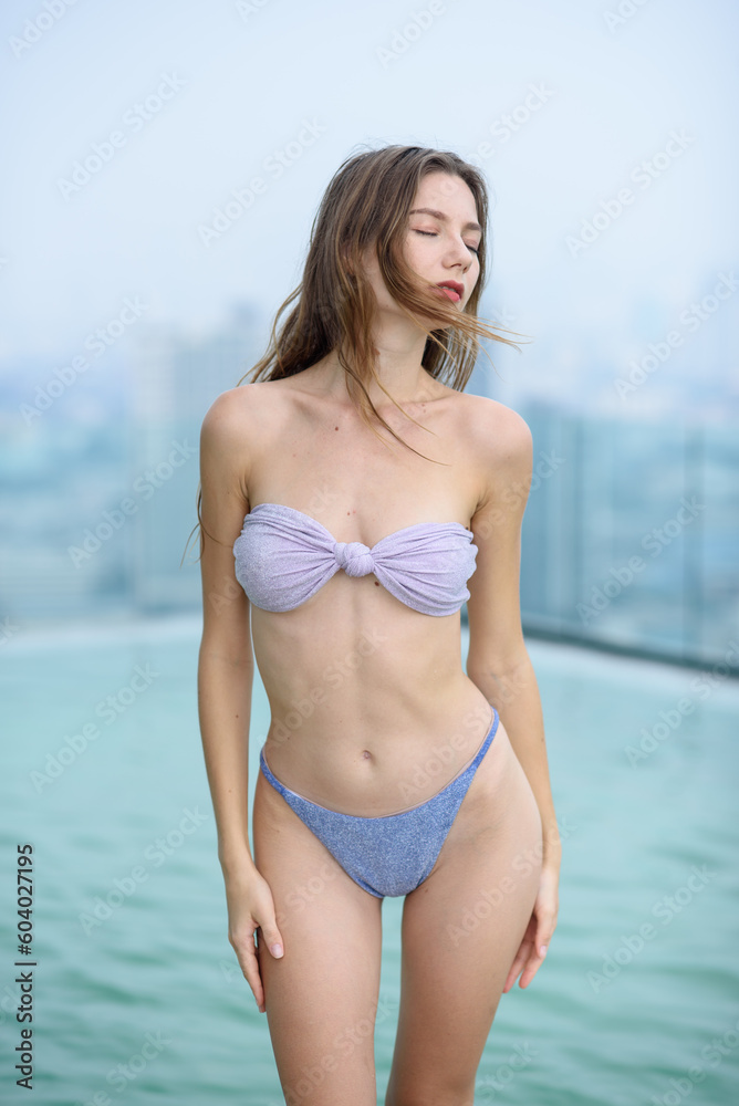 A girl in swimming wear in posing outdoor near a swimming pool A girl in swimming wear in posing outdoor near a swimming pool