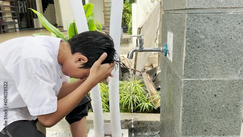 Muslim kid wiping the head  and cleanse ear when take ablution or wudu before praying salah photo